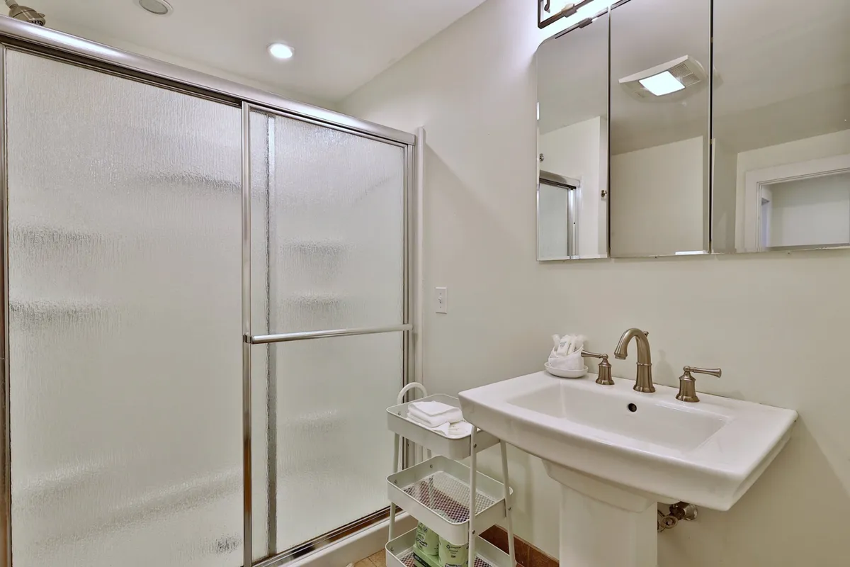 A modern bathroom with a glass shower enclosure, sink, and large mirror, all set in an inviting and refreshing atmosphere. The space is clean, bright, and practical for guests to refresh after outdoor adventures.